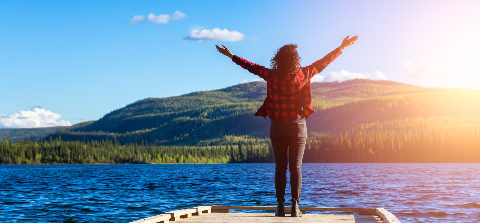 A person standing on a dock with her arms raised