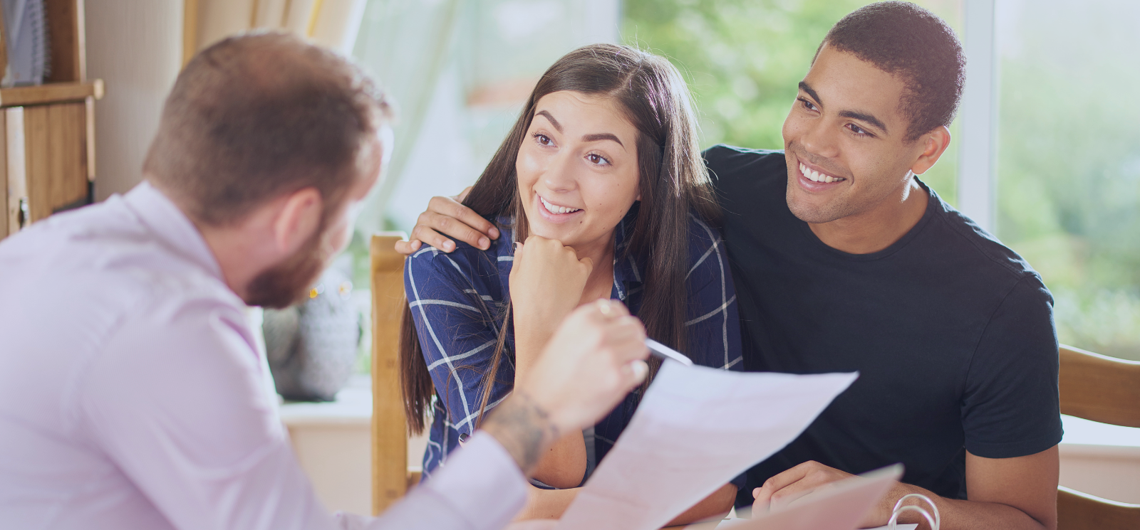 Couple reviewing mortgage prequalification documents with a loan officer at a table- discussing home financing options, interest rates, and loan eligibility during the home buying process.